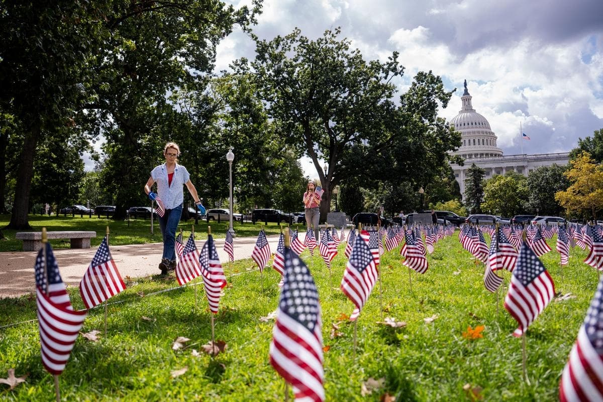 La gente coloca banderas estadounidenses para conmemorar los ataques terroristas del 11 de septiembre de 2001, en el Capitolio, el 11 de septiembre de 2025. (Madalina Kilroy/The Epoch Times)