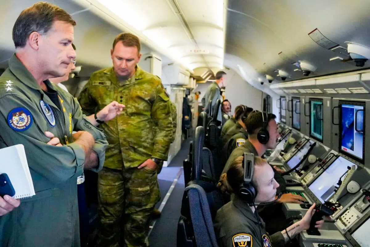 El almirante John C. Aquilino (izquierda), comandante del Comando Indo-Pacífico de EE. UU., observa videos de estructuras y edificios chinos a bordo de un avión de reconocimiento P-8A Poseidon de EE. UU. que sobrevuela las Islas Spratly en el Mar de China Meridional, el 20 de marzo de 2022. (Aaron Favila/AP Photo).