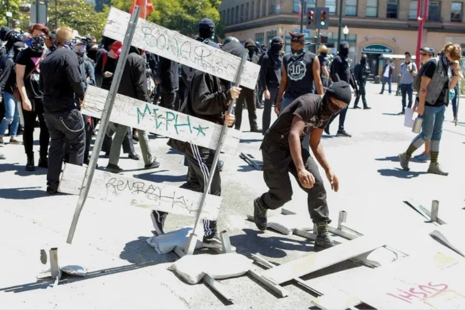 Militantes antifa derriban barricadas callejeras mientras marchan con contramanifestantes durante una manifestación de la alt-right en el centro de Berkeley, California, el 5 de agosto de 2018. (Amy Osborne/AFP/Getty Images).