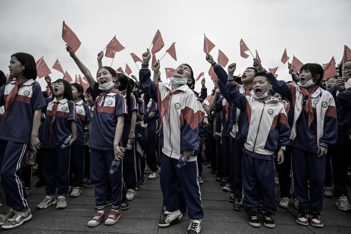 <em>Estudiantes vitorean mientras izan banderas nacionales chinas en una plaza de Shaoshan, en la provincia central de Hunan, China, el 27 de mayo de 2021. (Jade Gao/AFP vía Getty Images).</em>