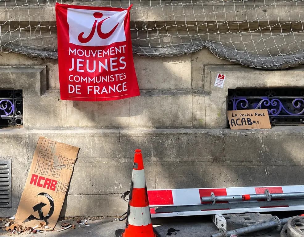 <em>Una pancarta del Movimiento Juvenil Comunista de Francia y un cartel de cartón con la inscripción "La policía nos está aplastando", con la hoz y el martillo, en la pared enrejada del Liceo Jacques Decour en París, el 1 de octubre de 2026. (Etienne Fauchaire/The Epoch Times).</em>