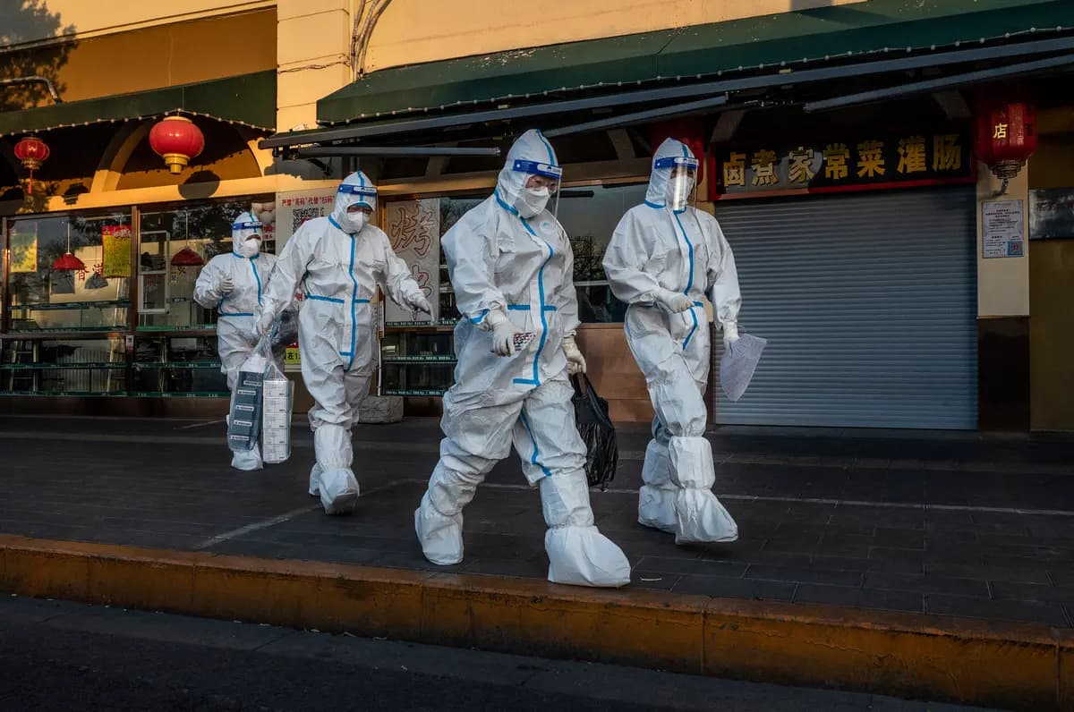 <em>Trabajadores encargados del control de la pandemia caminan por la calle junto a una tienda cerrada cerca de una comunidad cuyos residentes están bajo vigilancia sanitaria por COVID-19 en Beijing, el 4 de diciembre de 2022. (Kevin Frayer/Getty Images).</em>