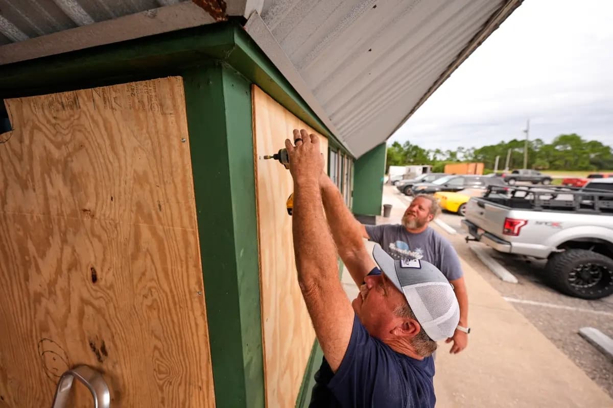 Mike Howard, en primer plano, y Joshua Brown colocan tablones en el bar deportivo Perdido Key Sports Bar ante la llegada del huracán Isaías a Perdido Key, Florida, el 8 de octubre de 2026. (Gerald Herbert / AP Photo)