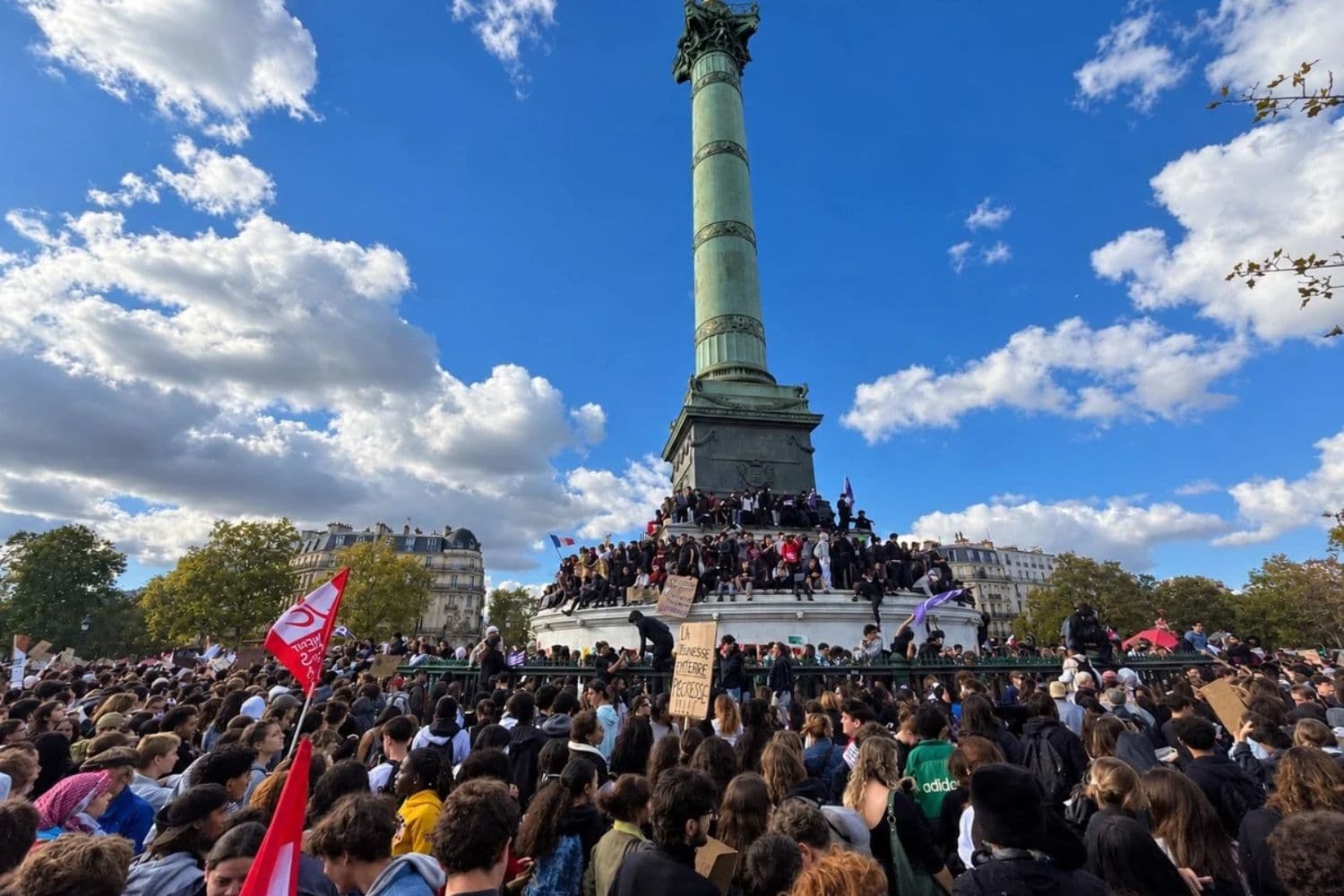 Los manifestantes se agolpan en la base de la Columna de Julio en la Place de la Bastille durante una protesta en un instituto mientras ondea una bandera del Movimiento Juvenil Comunista Francés en la izquierda en París el 8 de octubre de 2026. (Etienne Fauchaire/The Epoch Times).