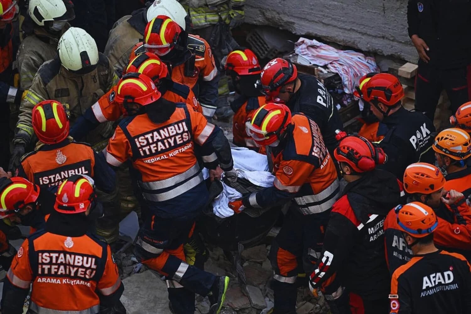 Bomberos y equipos de rescate turcos de la Presidencia Turca de Gestión de Desastres y Emergencias (AFAD) transportan a una víctima hallada entre los escombros de un edificio derrumbado en el distrito de Maltepe, en Estambul, el 8 de octubre de 2026. (Ozan KOSE / AFP vía Getty Images)