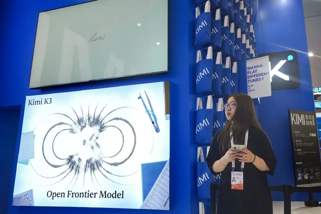 Una empleada se encuentra en un stand dedicado al Kimi K3 de la startup china de IA Moonshot durante la Conferencia Mundial de IA celebrada en Shanghái el 17 de julio de 2026. Según los analistas, China está tratando de ganar cuota de mercado al ofrecer modelos de peso abierto gratuitos. (Ng Han Guan/AP Photo)
