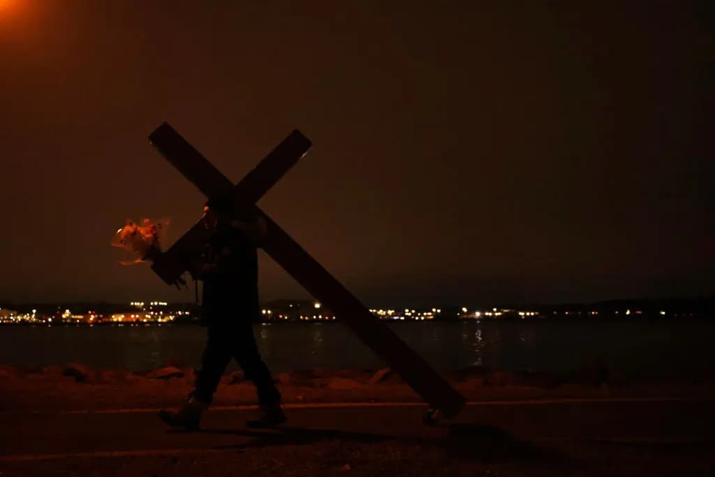 Dan Beazley lanza una ofrenda floral mientras sostiene unas flores tras una vigilia a la luz de las velas celebrada en memoria de las víctimas de la colisión del vuelo de DCA en el Rivergate City Park de Alexandria, Virginia, el 5 de febrero de 2025. (Kayla Bartkowski/Getty Images).