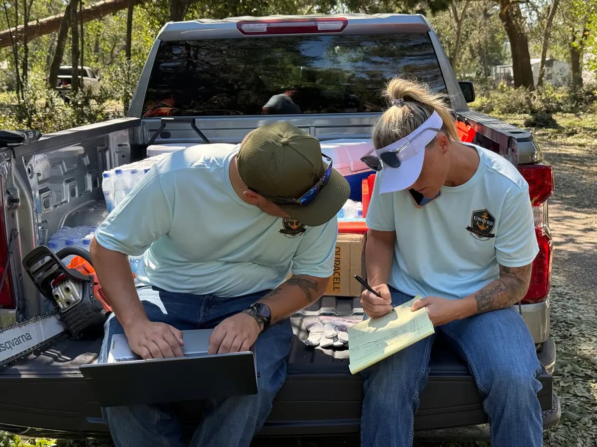 Los voluntarios de United Cajun Navy, Mason Adcock (izquierda) y Keisha Boyd (derecha), reciben y registran solicitudes de ayuda en el lugar de los hechos en Bagdad, Florida, el 11 de octubre de 2026. (T.J. Muscaro/The Epoch Times).