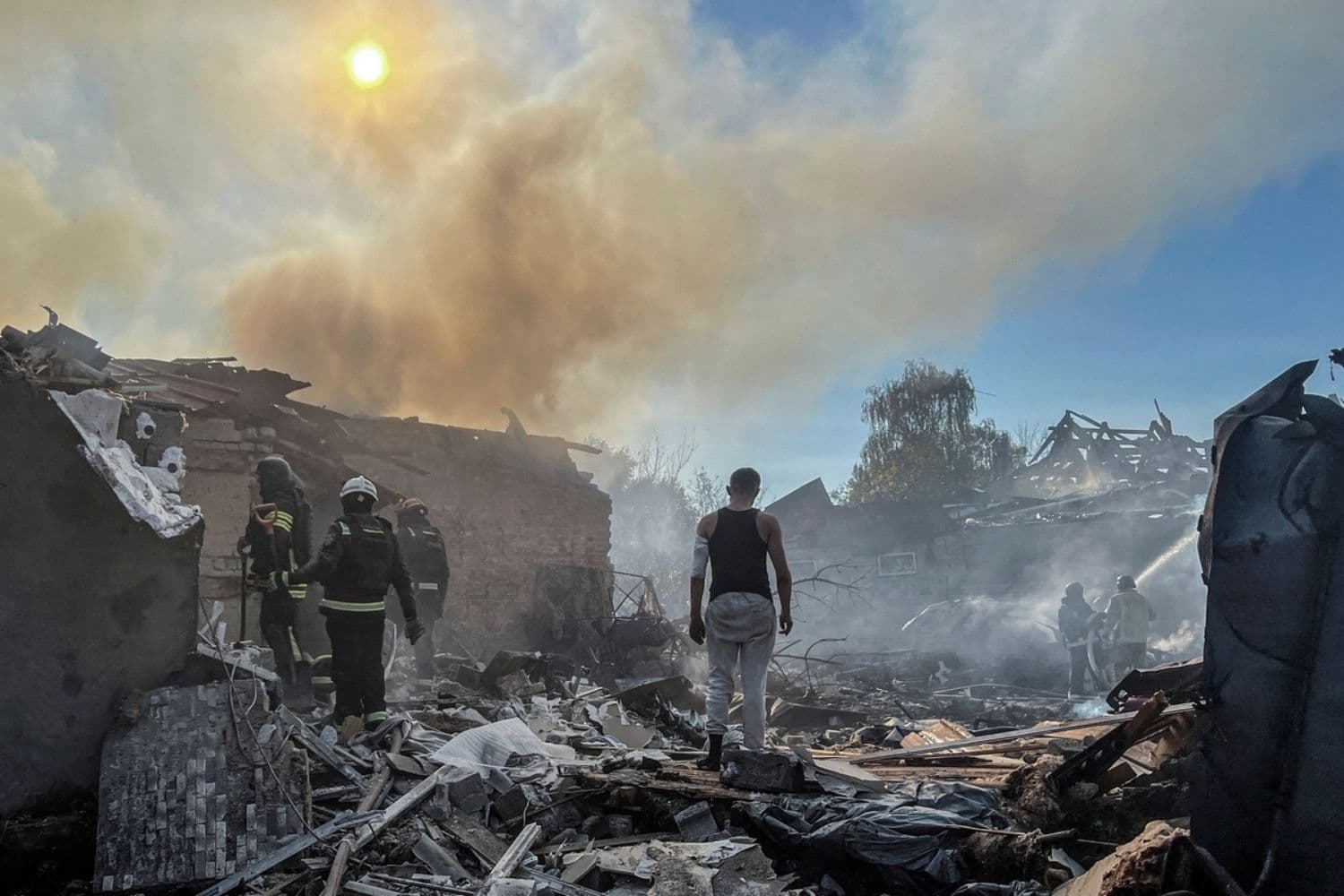 Un hombre se encuentra de pie entre los escombros mientras los bomberos trabajan en el lugar donde se encontraba su casa, alcanzada por un ataque aéreo ruso, en el marco de la invasión de Rusia a Ucrania, en Járkov, Ucrania, el 11 de octubre de 2026. (REUTERS/Volodymyr Pavlov)
