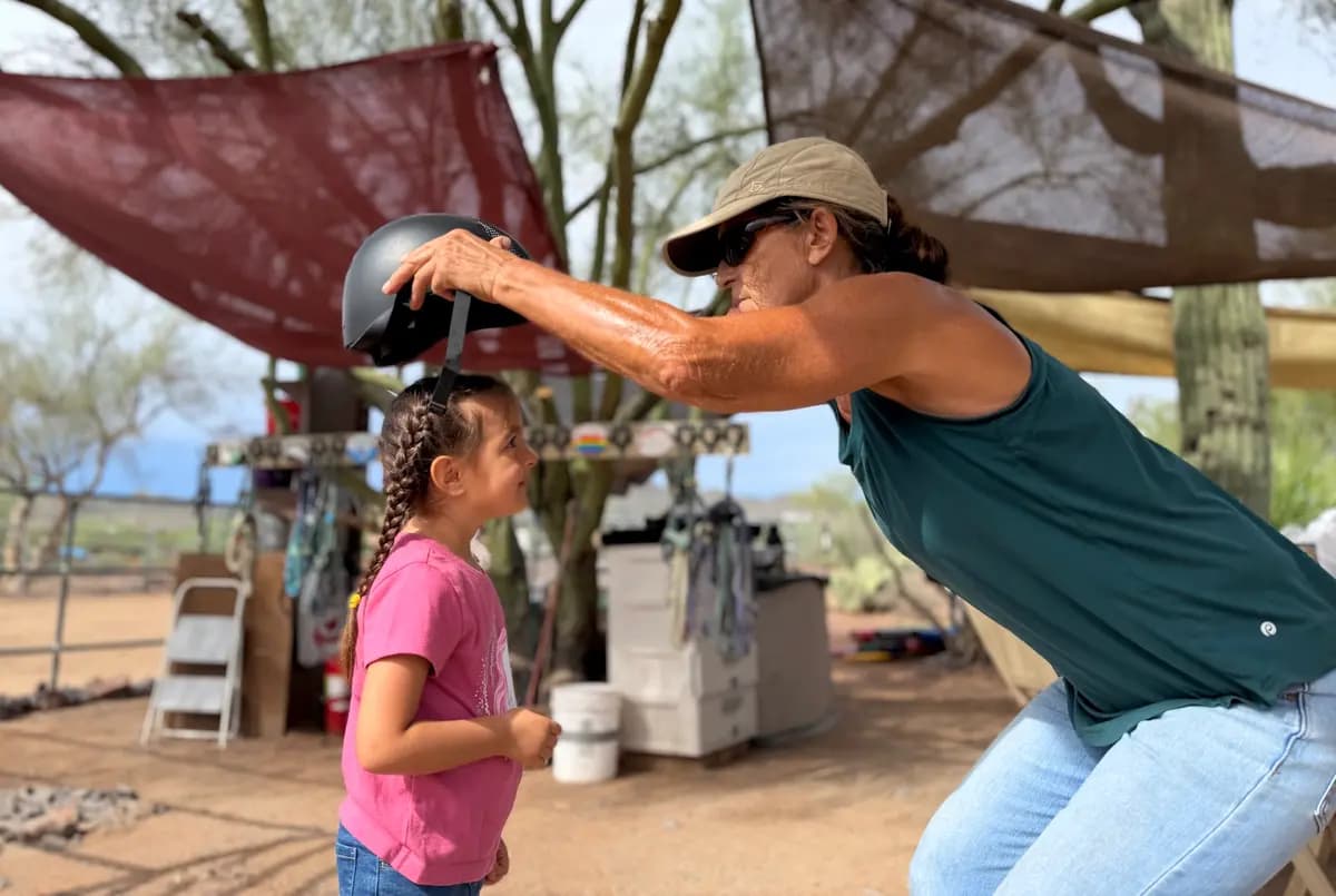 Sophie Rainer (derecha), fundadora de Donkeys of the Heart en Cave Creek, Arizona, ayuda a Dylan, de 4 años, con su casco de seguridad el 24 de septiembre de 2026. (Allan Stein/The Epoch Times)