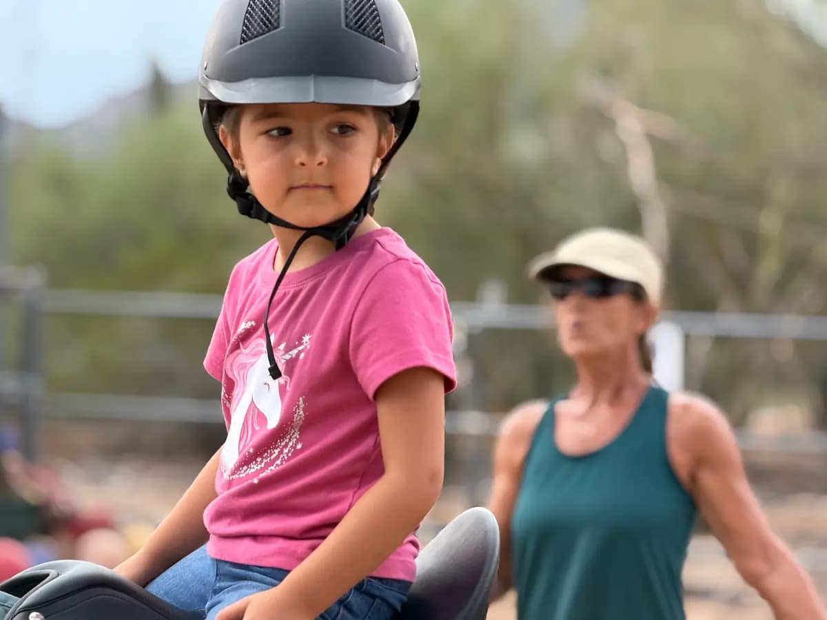 Dylan, de 4 años, dirige a su burro, Alfred, guiada por la instructora de equitación Sophie Rainer (derecha), el 24 de septiembre de 2026. (Allan Stein/The Epoch Times)