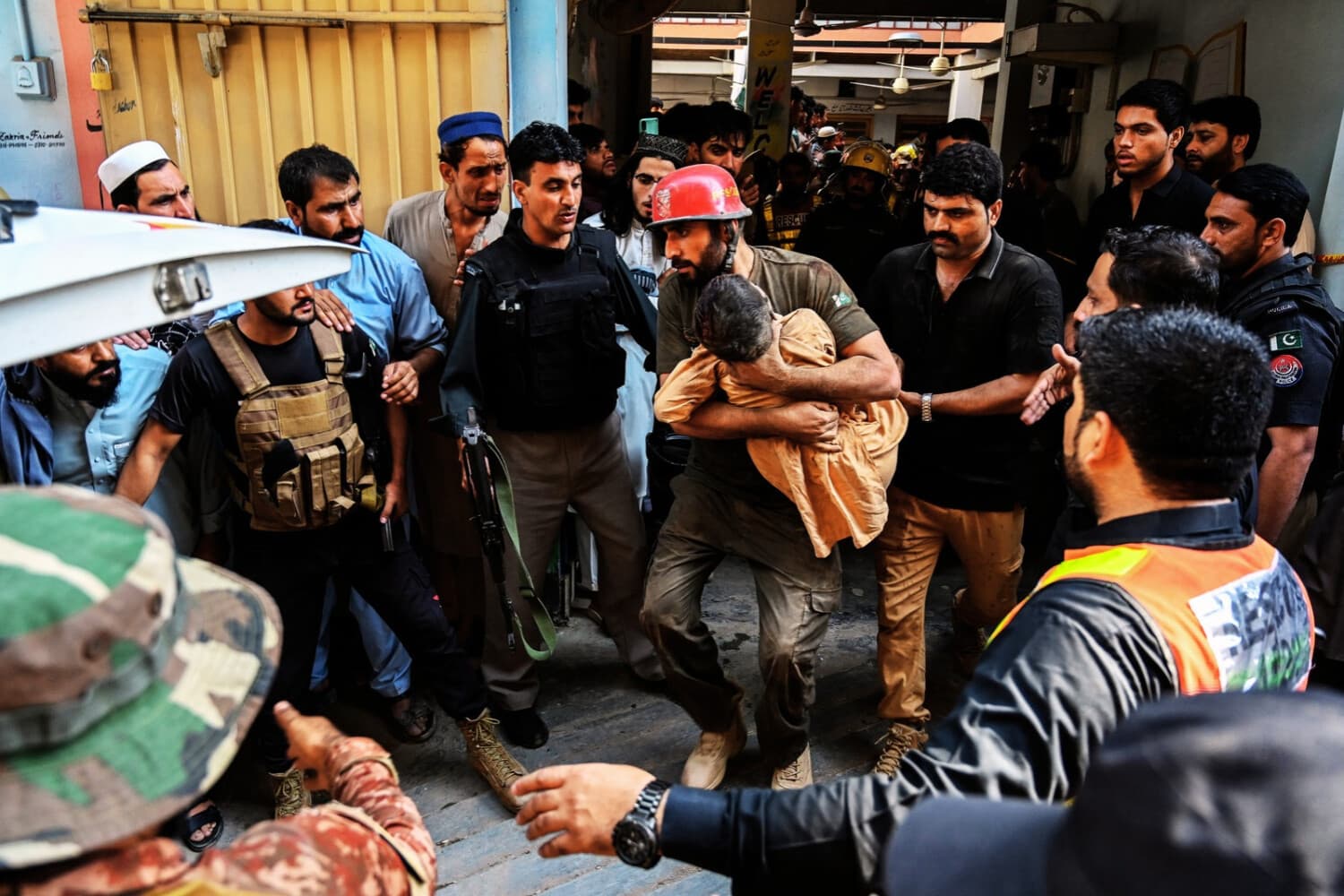 Un miembro del equipo de rescate (C) lleva a un niño en brazos durante una operación de búsqueda tras el derrumbe del techo de una escuela en Peshawar el 15 de octubre de 2026. (Abdul MAJEED / AFP vía Getty Images)
