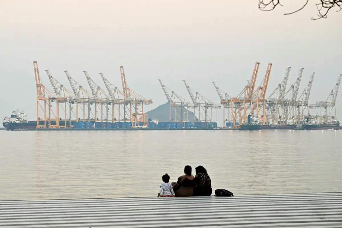 Una familia posa con un astillero como telón de fondo frente a la costa de Fujairah, en el Estrecho de Ormuz, en los Emiratos Árabes Unidos, el 25 de febrero de 2026. (Giuseppe Cacace/AFP vía Getty Images).