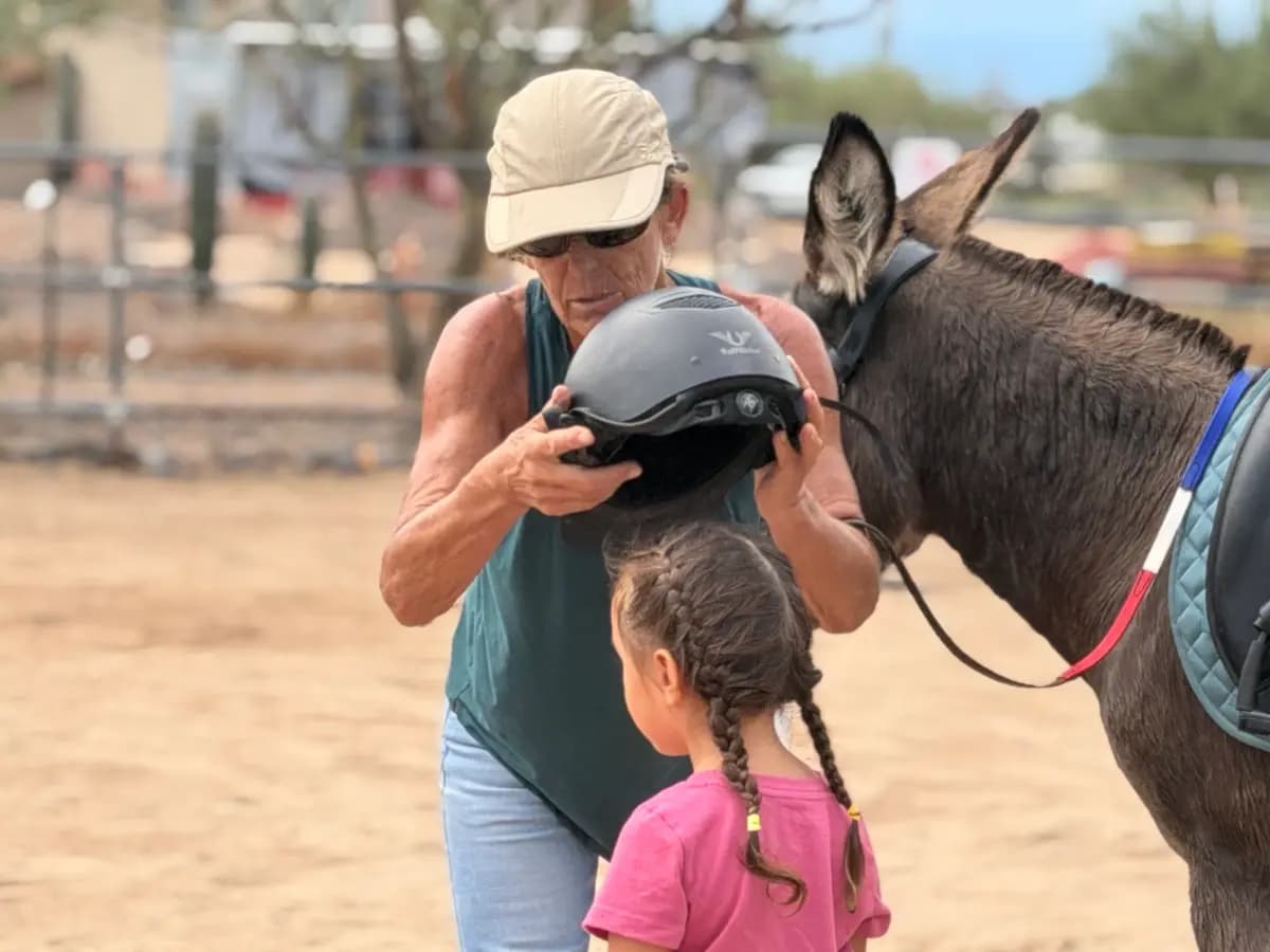 Sophie Rainer (izquierda) le quita el casco de seguridad a Dylan, de 4 años, al final de su clase de equitación el 24 de septiembre de 2026. (Allan Stein/The Epoch Times)
