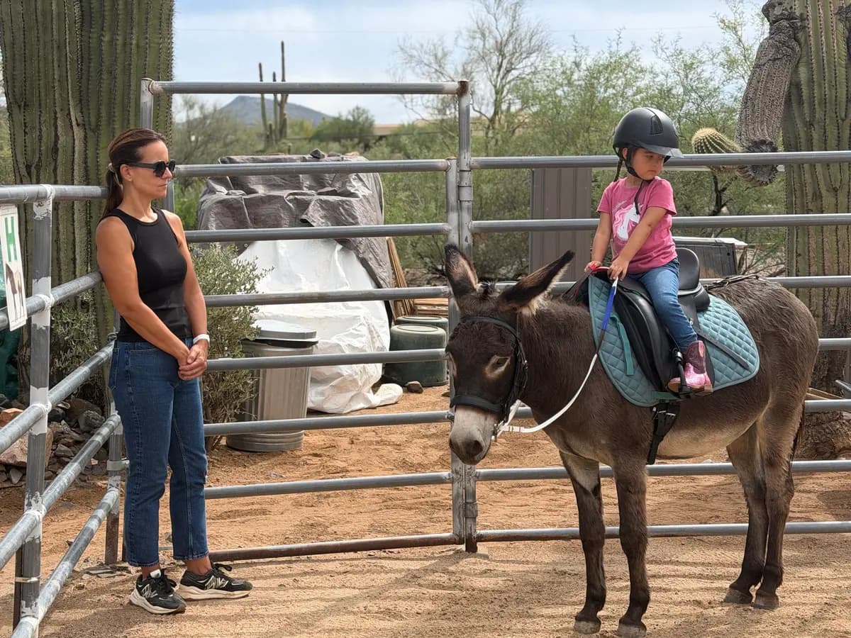 Amanda Koch (izquierda), voluntaria de Donkeys of the Heart en Cave Creek, Arizona, aconseja a Dylan, de 4 años, sobre su lección de equitación el 24 de septiembre de 2026. (Allan Stein/The Epoch Times)