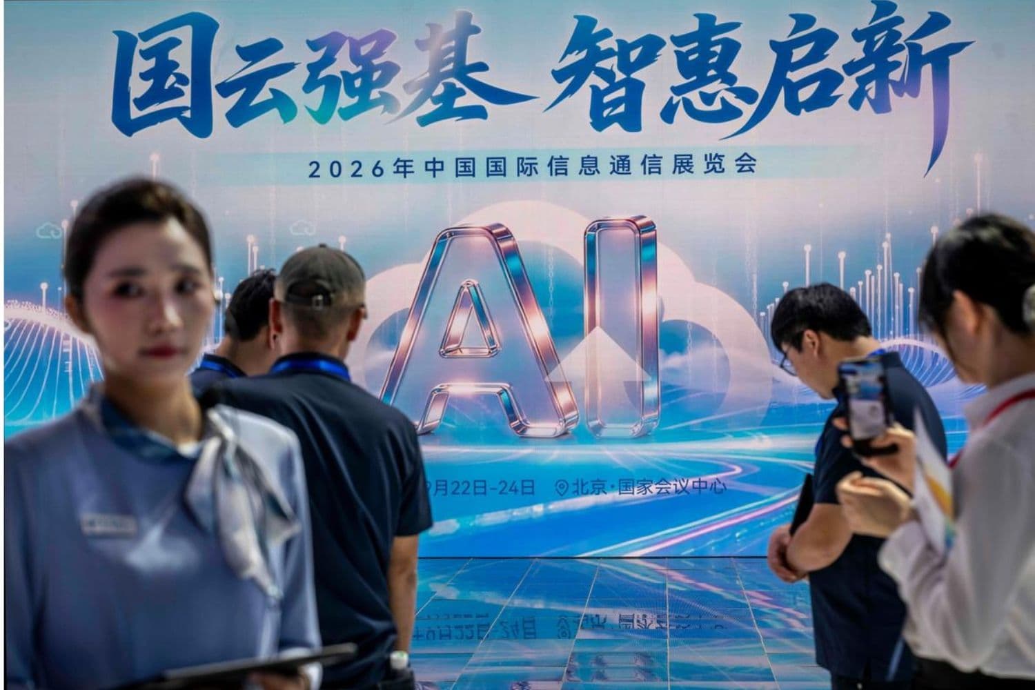 Una pantalla con IA como anfitriona, mientras los visitantes se reúnen en un stand de una empresa china de telecomunicaciones en la PT Expo en Beijing el 22 de septiembre de 2026. (Kevin Frayer/Getty Images)