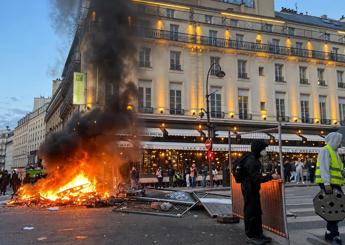 <em>Un manifestante enmascarado levanta una barricada junto a escombros en llamas frente al Café Le Brébant en el Boulevard Poissonnière, en medio de las violentas protestas que sacudieron París el 17 de octubre de 2026. (Etienne Fauchaire/The Epoch Times).</em>