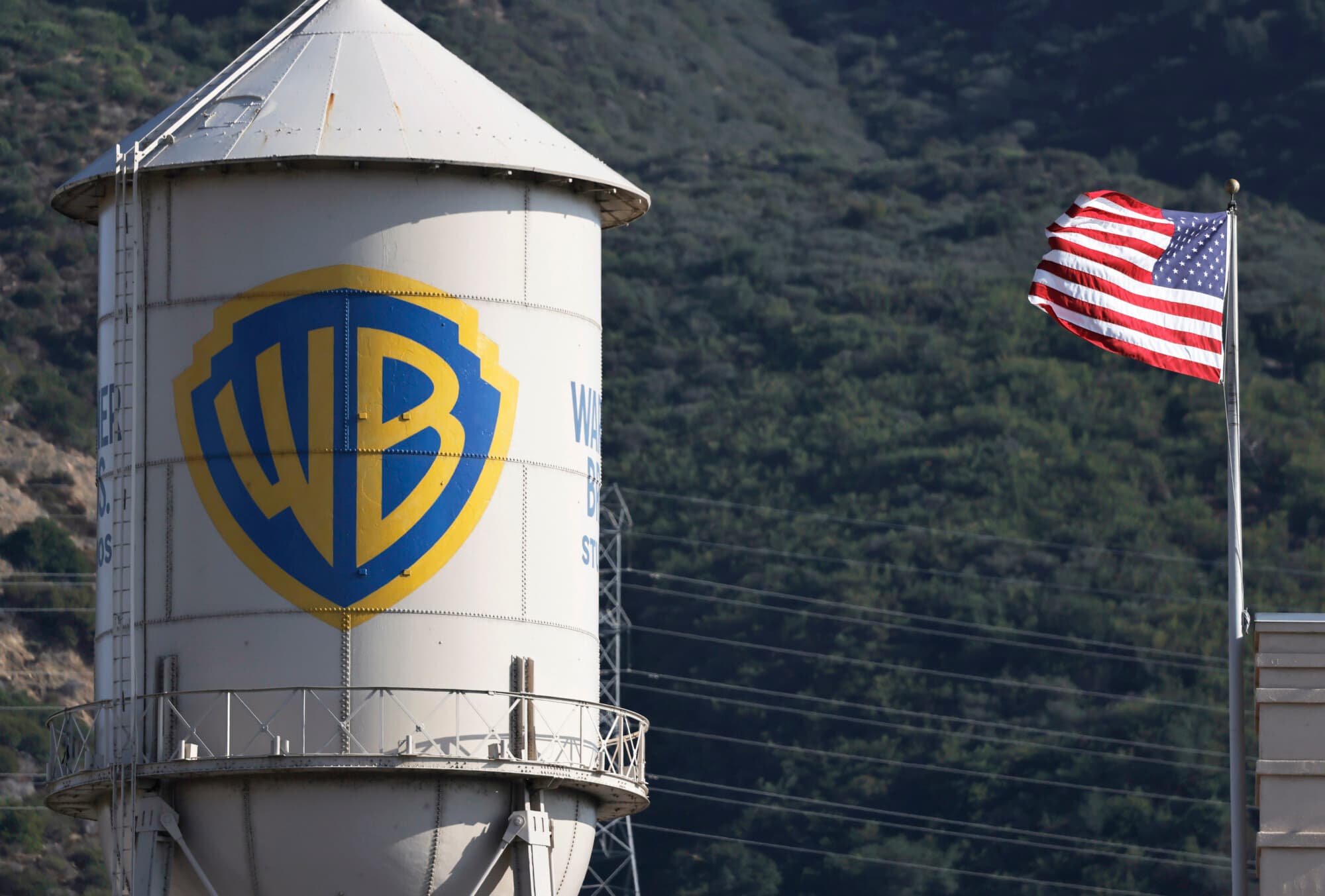 El logotipo de Warner Bros. se ve en la torre de agua de los estudios Warner Bros., mientras ondea una bandera estadounidense el 21 de septiembre de 2026 en Burbank, California. (Mario Tama/Getty Images)