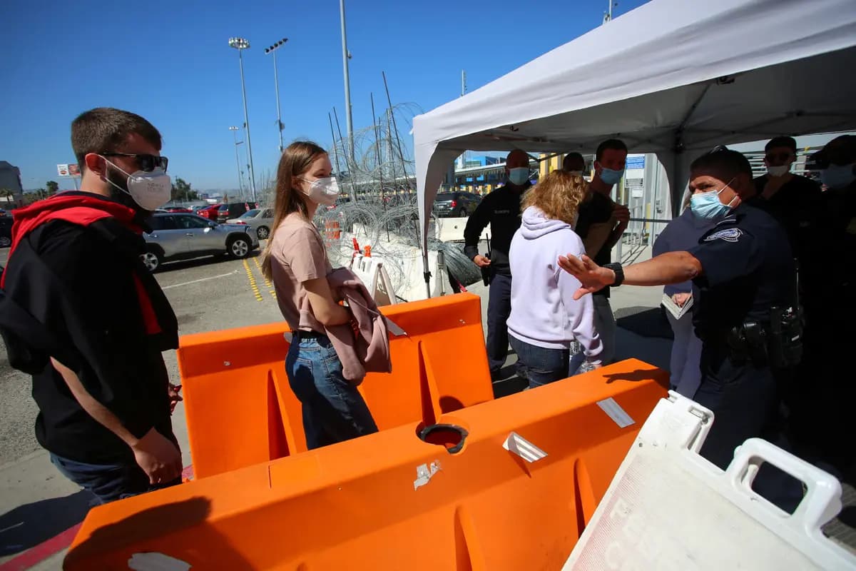 Un agente de la Oficina de Aduanas y Protección Fronteriza de EE. UU. señala con un gesto a una familia ucraniana en el puerto de entrada de San Ysidro, en la frontera entre EE. UU. y México, en Tijuana, México, el 15 de marzo de 2022. (Jorge Duenes/Reuters).