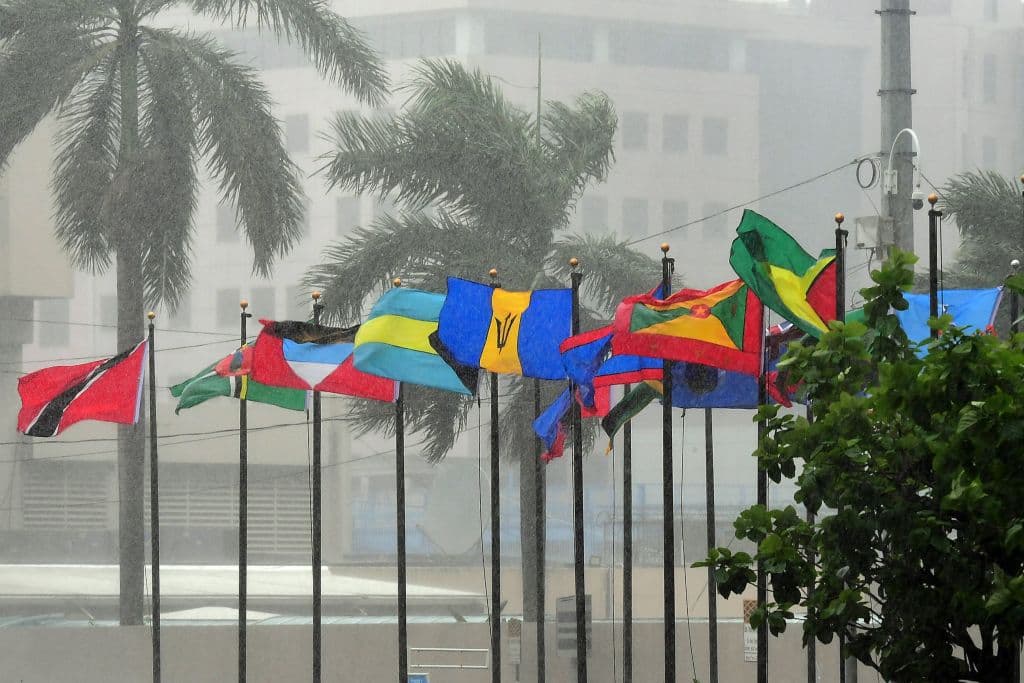 Las banderas de varias naciones de CARICOM ondean bajo la intensa lluvia a la entrada del Hotel Hyatt Regency en Puerto España en el marco de una reunión de Jefes de Gobierno de CARICOM. (Foto de Diario Trinidad Express/AFP vía Getty Images)