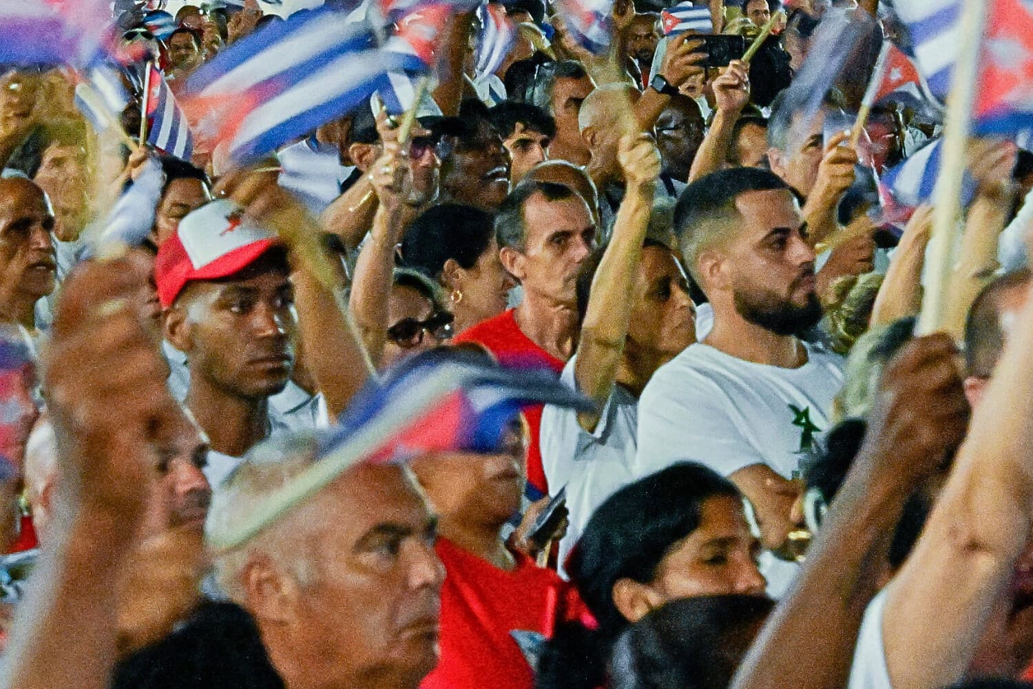 Cubanos agitan banderas de papel frente a una valla publicitaria en la que aparece el expresidente (2006-2018) Raúl Castro, durante la celebración del 73.º aniversario del asalto guerrillero al Cuartel de Moncada, liderado por el difunto líder Fidel Castro y considerado el inicio de la Revolución Cubana, en Pinar del Río, Cuba, el 26 de julio de 2026. (YAMIL LAGE / AFP vía Getty Images)