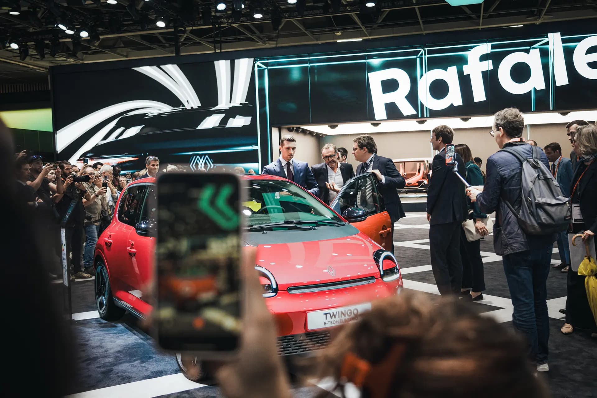 Jordan Bardella (C), presidente del partido político Agrupación Nacional, de pie frente a un Renault Twingo en el Salón del Automóvil de París el 16 de octubre de 2026. Aproximadamente el 40 por ciento del valor del Twingo, incluyendo su batería y su motor, proviene de componentes chinos. (Carine Schmitt/Hans Lucas/AFP vía Getty Images).