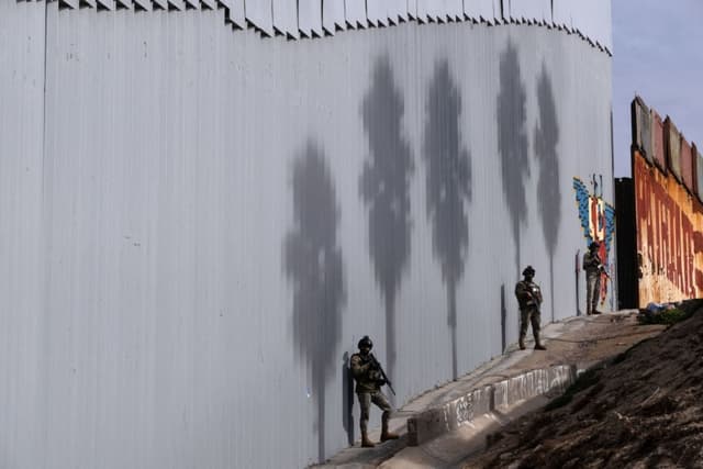 Oficiales de la Marina mexicana custodian un tramo entre las secciones nueva y antigua del muro fronterizo entre Estados Unidos y México en Playas de Tijuana, estado de Baja California, México, el 18 de diciembre de 2023. (GUILLERMO ARIAS/AFP vía Getty Images)