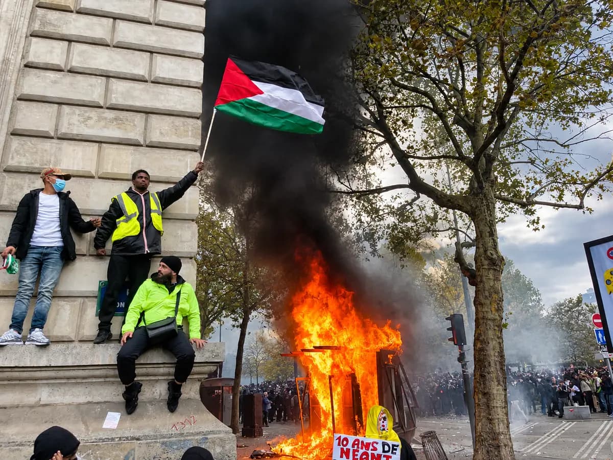 Un manifestante ondea una bandera palestina junto a un quiosco de periódicos en llamas en la Plaza de la República de París durante las manifestaciones de extrema izquierda del 17 de octubre de 2026. (Etienne Fauchaire/The Epoch Times)