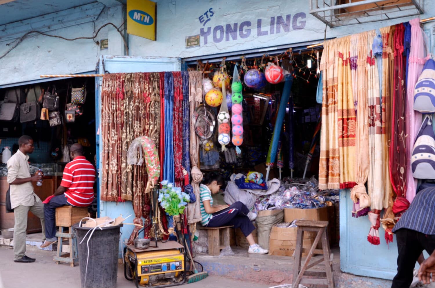 Personas fuera y dentro de negocios de propiedad china. (Junior D.Kannah/AFP vía Getty Images)