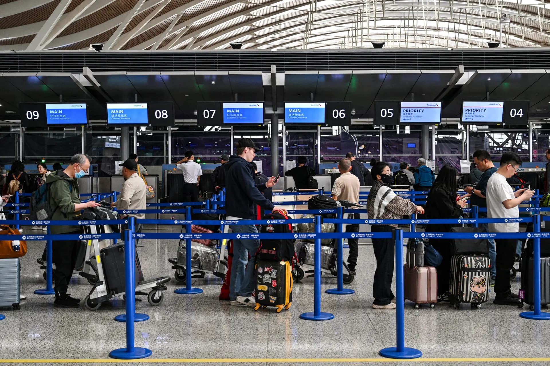 Pasajeros esperan en un mostrador de American Airlines en el Aeropuerto Internacional de Shanghái-Pudong el 17 de abril de 2025. (Héctor Retamal/AFP vía Getty Images)