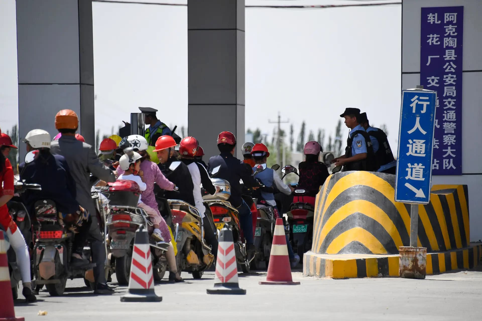Unos viajeros esperan en un control policial en una carretera cercana a unas instalaciones que se cree que son un campo de reeducación donde se detiene principalmente a minorías musulmanas, en la región de Xinjiang (China), el 4 de junio de 2019. Un analista calificó la región como "un campo de pruebas para la represión". (Greg Baker/AFP vía Getty Images)