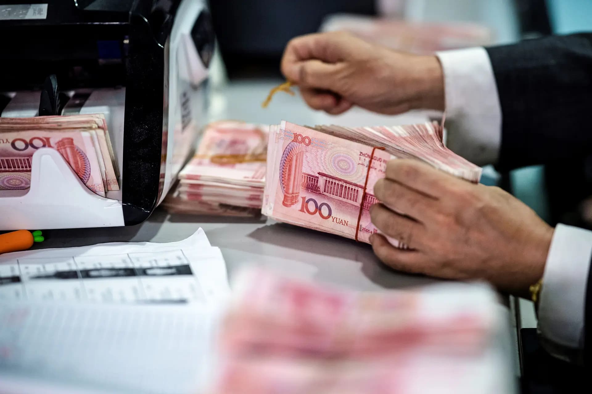 Un empleado cuenta billetes de 100 yuanes en un banco de Shanghái el 8 de agosto de 2018. Según las nuevas normas chinas, "cualquier persona que tenga depósitos de 10 millones de yuanes [unos 1.4 millones de dólares] o más a su nombre podría ser sometida a controles fronterizos en cualquier momento y en cualquier lugar, y se le podría prohibir salir del país", explicó el comentarista chino Cai Shenkun a The Epoch Times. (Johannes Eisele/AFP vía Getty Images)