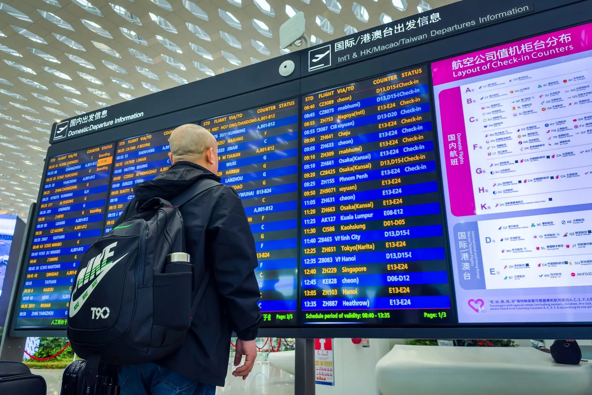 Un viajero observa un panel digital de información de salidas que muestra los horarios de vuelos nacionales e internacionales en el Aeropuerto Internacional de Shenzhen Bao'an, en Shenzhen (China), el 13 de abril de 2025. (Cheng Xin/Getty Images)
