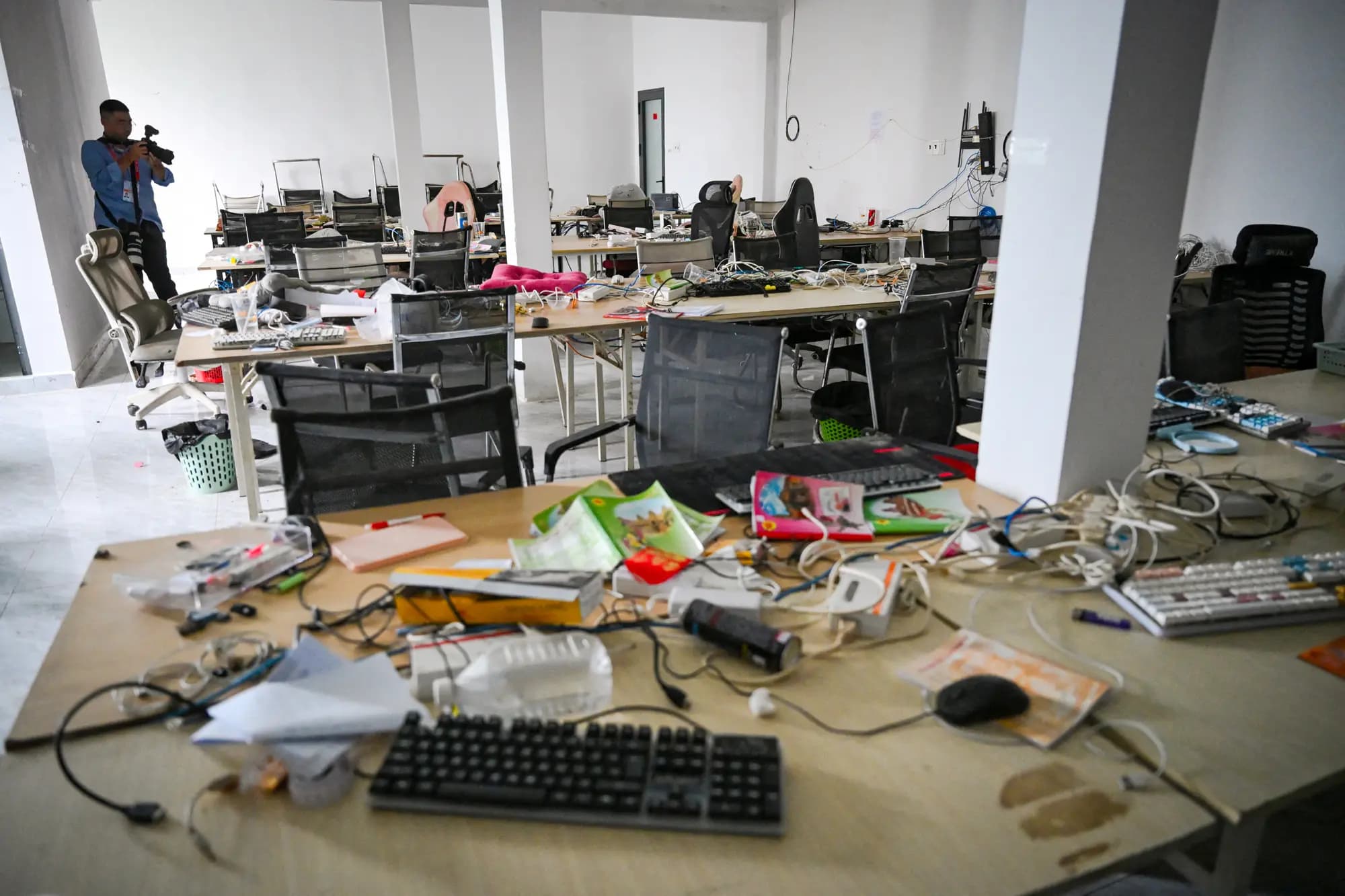 <em>(Arriba) Complejo de un centro de estafas cibernéticas clausurado en la provincia de Prey Veng, Camboya, el 21 de septiembre de 2026. (Abajo) Un periodista toma fotografías de equipos abandonados en un centro de estafas cibernéticas clausurado en Camboya el 21 de septiembre de 2026. (Suy Se/AFP vía Getty Images, Tang Chhin Sothy/AFP vía Getty Images).</em>