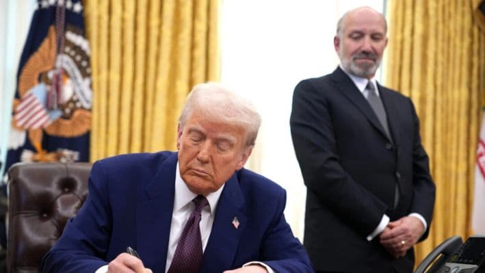 El presidente Donald Trump, acompañado por el candidato a secretario de Comercio Howard Lutnick, firma una orden ejecutiva sobre aranceles recíprocos en la Oficina Oval de la Casa Blanca en Washington, el 13 de febrero de 2025. (Andrew Harnik/Getty Images)