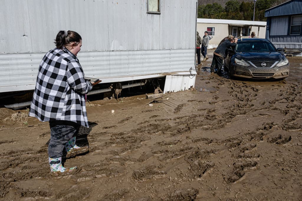 Los familiares de Kathy Kinney se reúnen alrededor de ella en un vehículo cerca de su casa en Ramsey Mobile Home Park luego de las tormentas de lluvia que causaron inundaciones el 17 de febrero de 2025 en Pikeville, Kentucky (EE. UU.). (Jon Cherry/Getty Images)