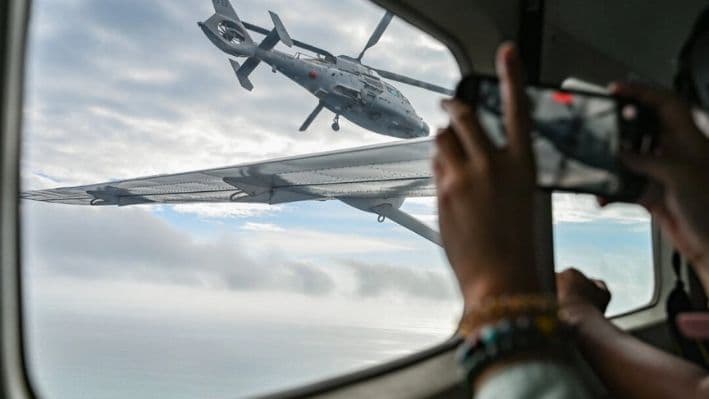 Una aeronave identificada por la Guardia Costera de Filipinas como un helicóptero de la Armada china (L) vuela cerca del avión de la Oficina de Pesca y Recursos Acuáticos (BFAR) durante un vuelo de reconocimiento aéreo en Scarborough Shoal, en el Mar de China Meridional, el 18 de febrero de 2025. (Jam Sta Rosa/AFP vía Getty Images)
