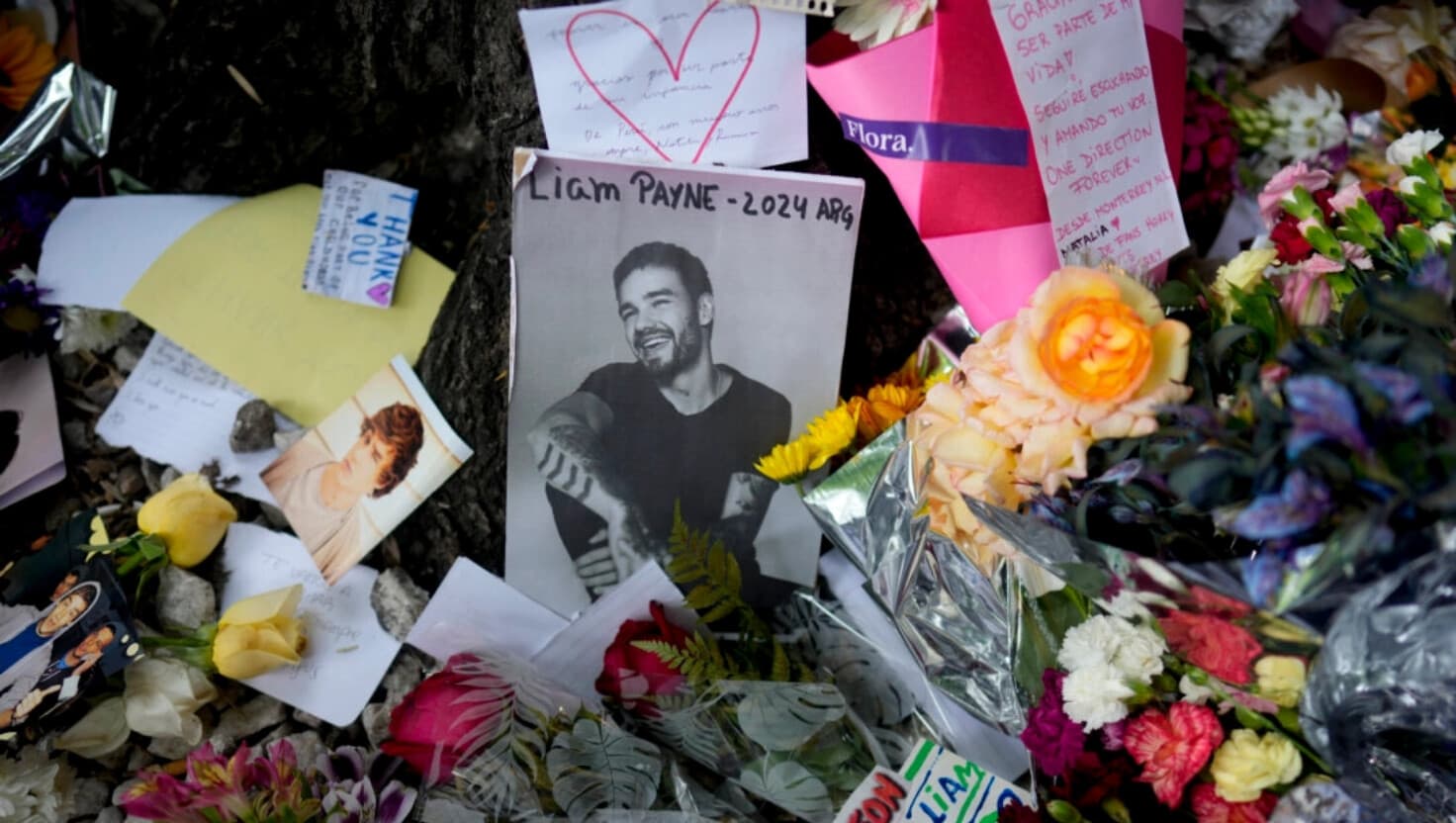 Una foto del ex cantante de One Direction Liam Payne rodeada de flores y velas como parte de un memorial improvisado frente al hotel donde cayó desde un balcón y murió, en Buenos Aires, Argentina, el 17 de octubre de 2024. (Natacha Pisarenko/AP Photo).