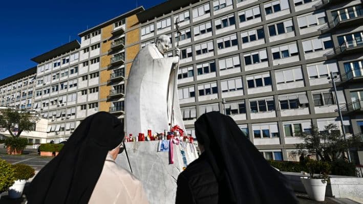 Monjas rezan frente a la estatua del Papa Juan Pablo II en la entrada del Hospital Gemelli, donde permanece hospitalizado el Papa Francisco, Roma, Italia, 03 de marzo de 2025.(EFE/EPA/RICCARDO ANTIMIANI)