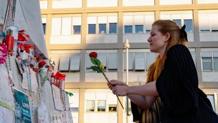 Una mujer coloca una flor frente a la estatua de Juan Pablo II en la entrada del Hospital Gemelli, donde está hospitalizado el Papa Francisco, en Roma, Italia, 04 de marzo de 2025. (EFE/EPA/FABIO FRUSTACI)
