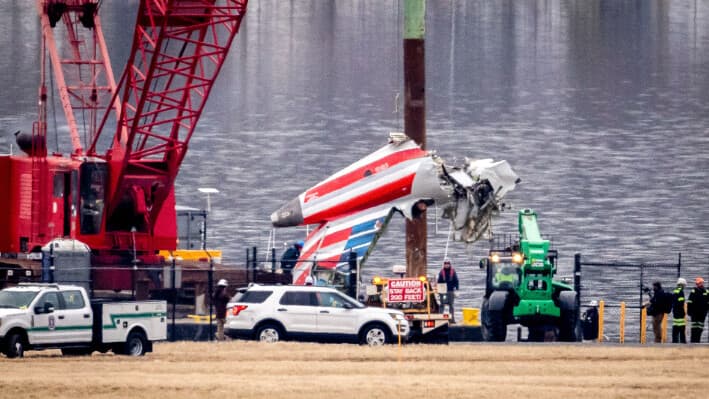 Una grúa descarga fragmento de un naufragio de un barco de salvamento a un camión de plataforma, cerca del lugar del naufragio en el río Potomac, tras una colisión en el aire entre un avión de American Airlines y un helicóptero Black Hawk, en el Aeropuerto Nacional Ronald Reagan de Washington, en Arlington, Virginia, el 5 de febrero de 2025. (Ben Curtis/AP Photo).