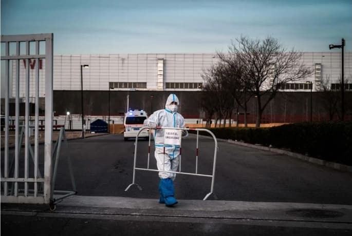 Un trabajador de control de epidemias usa EPP para protegerse contra la propagación del COVID-19 mientras coloca una barricada en una carretera después de permitir que una ambulancia ingresara a un centro de cuarentena del gobierno en Beijing, China, el 7 de diciembre de 2022. (Kevin Frayer/Getty Images)