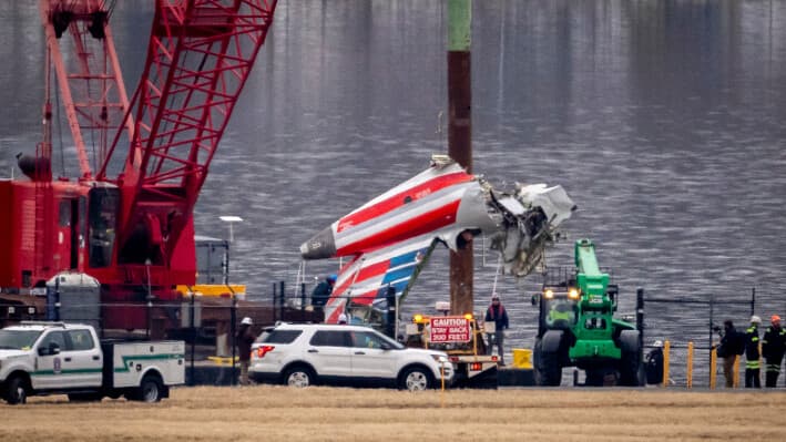 Una grúa descarga un trozo de los restos de un barco de salvamento en un camión de plataforma, cerca del lugar del accidente en el río Potomac de una colisión en el aire entre un avión de American Airlines y un helicóptero Black Hawk, en el Aeropuerto Nacional Ronald Reagan de Washington en Arlington, Virginia, el 5 de febrero de 2025. (Ben Curtis/AP Photo).