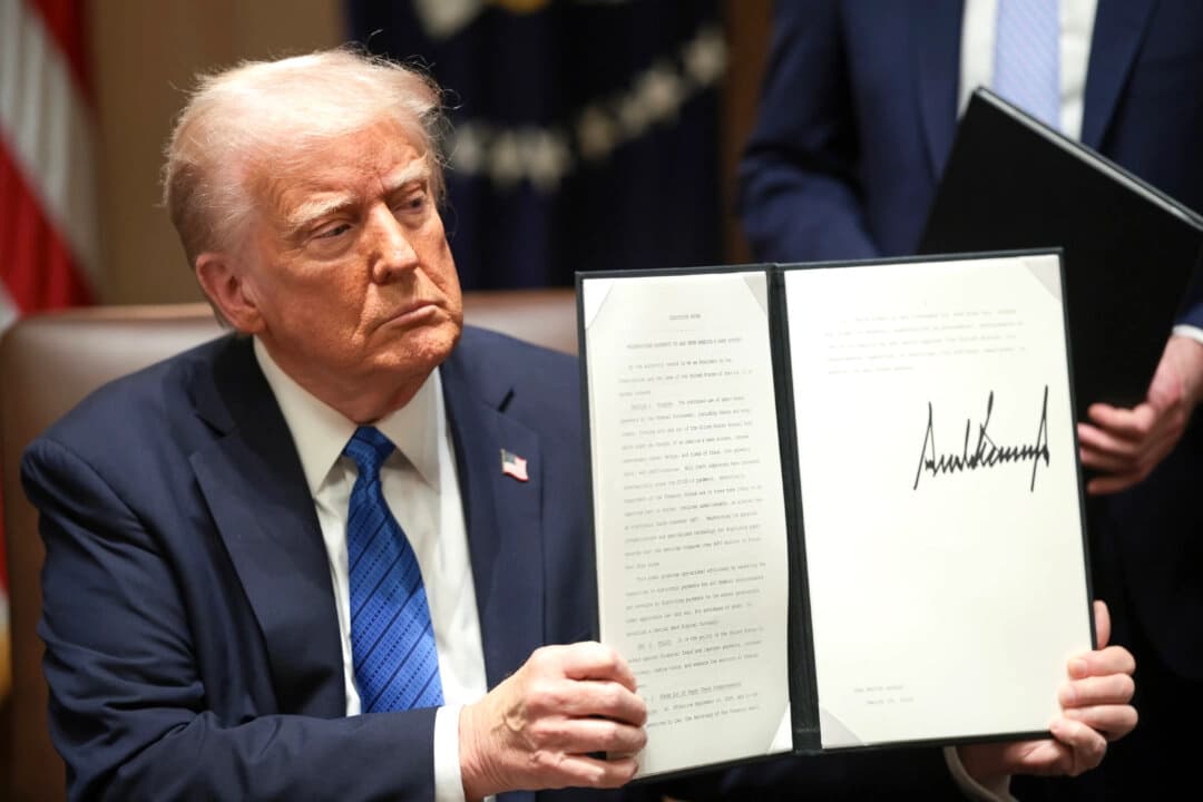 El presidente Donald Trump sostiene los documentos que firmó en la Sala del Gabinete de la Casa Blanca, el 25 de marzo de 2025. (Win McNamee/Getty Images)