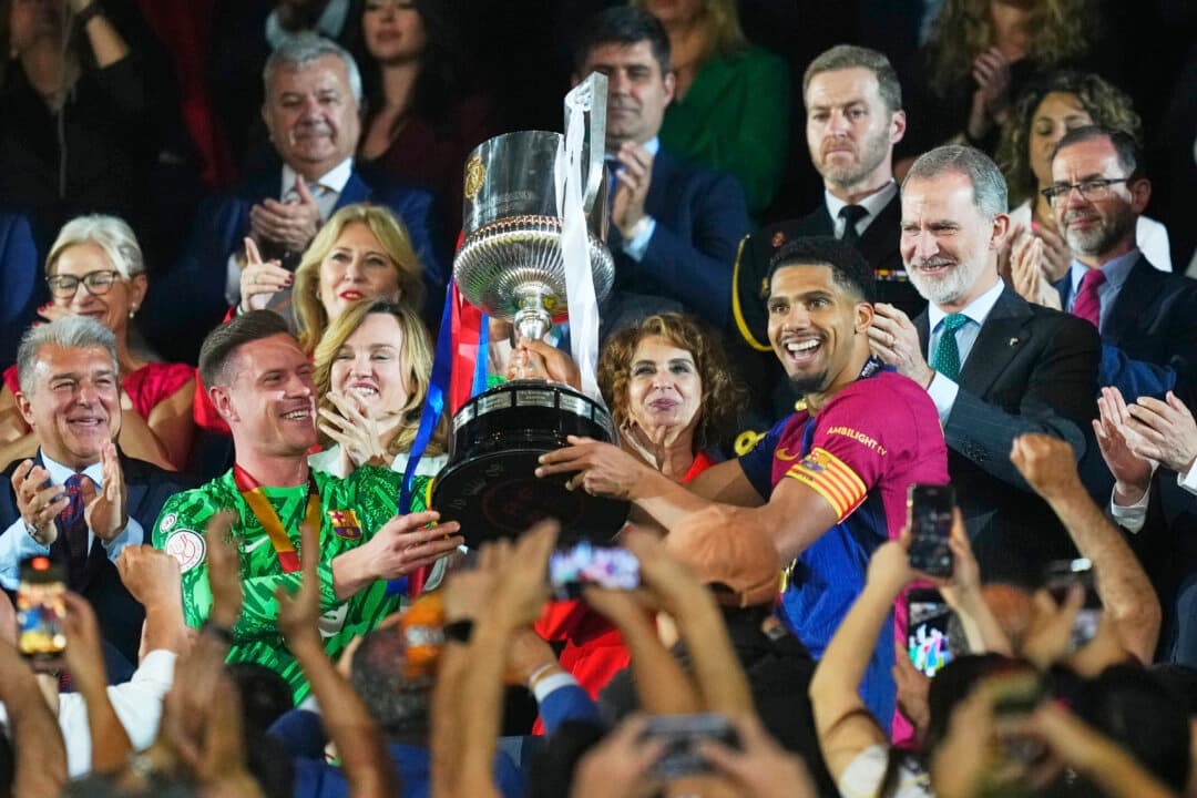 Ronald Araujo, centro-derecha, y Marc-Andre ter Stegen, portero del Barcelona, levantan el trofeo tras ganar la final de la Copa del Rey de fútbol entre el Barcelona y el Real Madrid en el estadio de La Cartuja de Sevilla, España, el 27 de abril de 2025. (Jose Breton/AP Photo)