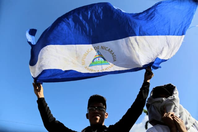 Un hombre sostiene una bandera de Nicaragua durante una misa campal celebrada por la Iglesia Católica en favor de la paz en Nicaragua, en Managua, el 1 de enero de 2019. (INTI OCON/AFP vía Getty Images)