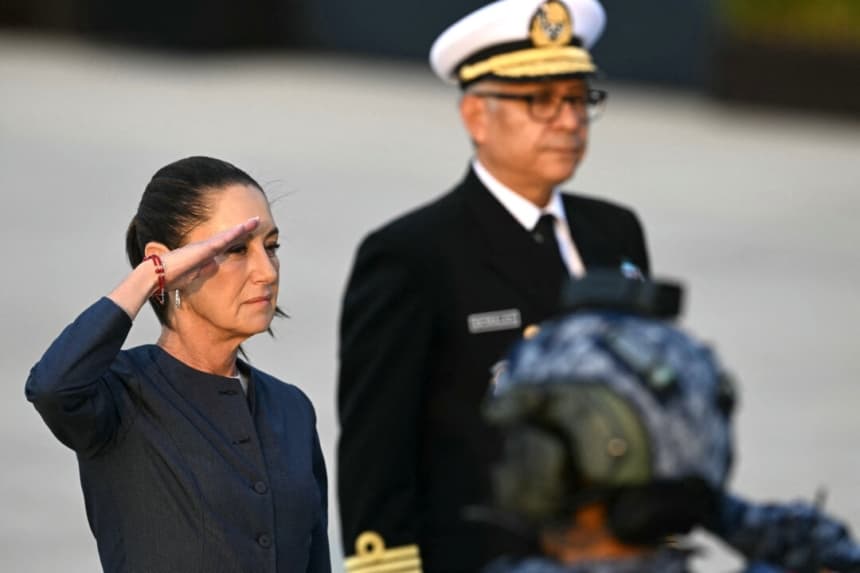 La presidenta de México, Claudia Sheinbaum, saluda a la bandera mexicana junto al titular de la Secretaría de Marina, Raymundo Morales, durante la ceremonia de apertura de la Feria Aeroespacial México 2025 en la Base Aérea de Santa Lucía, cerca de Ciudad de México, el 22 de abril de 2025. (YURI CORTEZ/AFP)