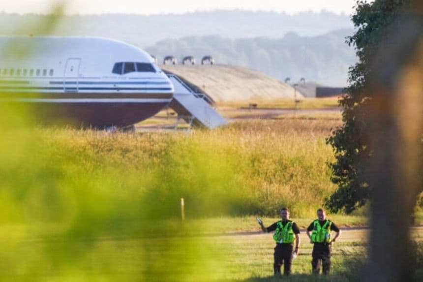 Agentes de policía de pie cerca de un avión reportado por los medios británicos como el primero en transportar inmigrantes ilegales a Ruanda en la base MoD Boscombe Down en Wiltshire, Reino Unido, el 14 de junio de 2022. (Hannah McKay/Reuters)