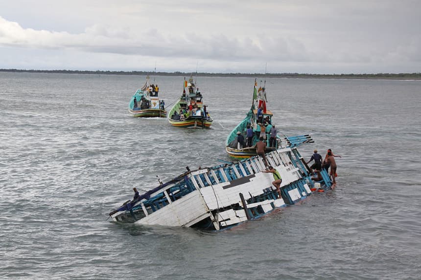 Rescatistas revisan los restos de un barco de traficantes de personas que se vio medio sumergido en una foto de archivo. (AFP/AFP vía Getty Images)