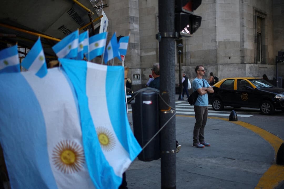 Un hombre se encuentra junto a una tienda callejera que vende banderas argentinas, en el centro de Buenos Aires, Argentina, el 14 de abril de 2025. (Agustín Marcarian/Reuters)